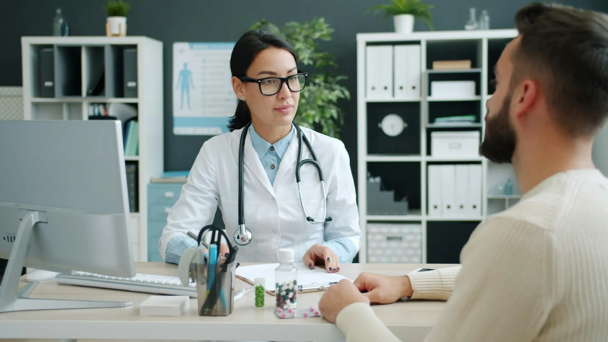 Une médecin échange avec un patient assis face à elle dans un cabinet clair et ordonné.